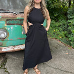 A woman wearing the black Solid Linen Cut-Out Midi Dress in front of a vintage teal Volkswagen bus.