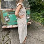 A woman wearing the oatmeal Stripe Sleeveless Ruffle Jumpsuit in front of a vintage teal Volkswagen bus.