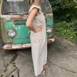 A woman wearing the oatmeal Stripe Sleeveless Ruffle Jumpsuit in front of a vintage teal Volkswagen bus.