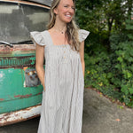 A woman wearing the black Stripe Sleeveless Ruffle Jumpsuit in front of a vintage teal Volkswagen bus.