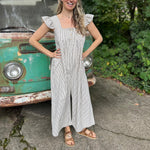 A woman wearing the black Stripe Sleeveless Ruffle Jumpsuit in front of a vintage teal Volkswagen bus.