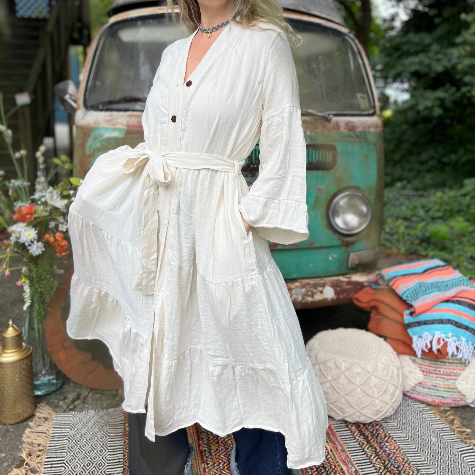 A woman wearing the white Organic Tiered Maxi Kimono Wrap Dress in front of a vintage Volkswagen bus.