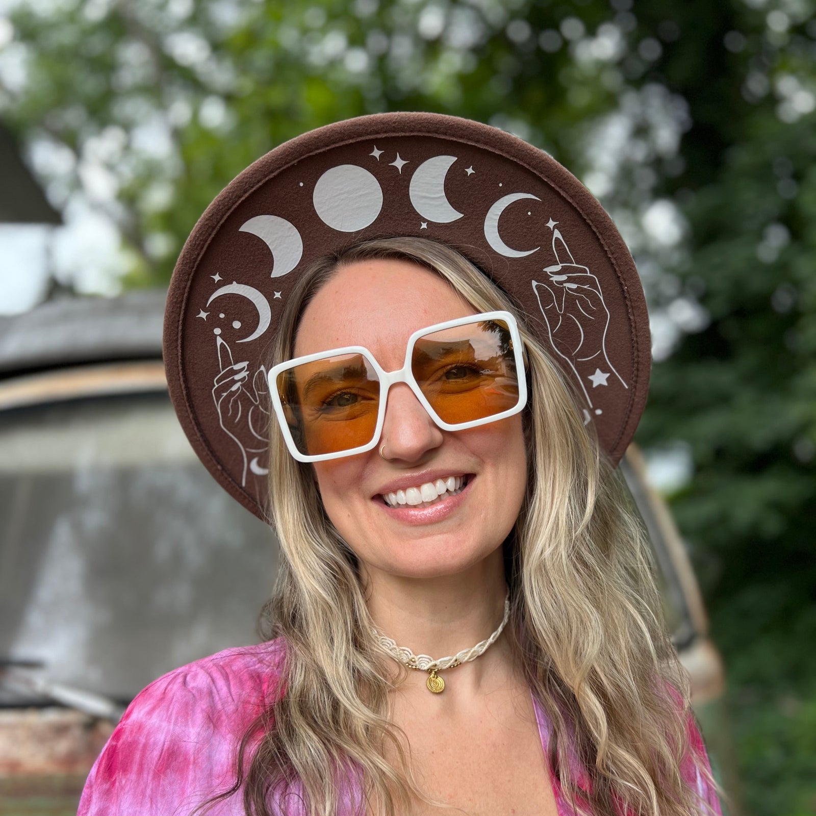 A woman wearing the white Kelso 70s Sunglasses with a brown hat and pink kimono.