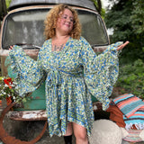A woman wearing the green Hippie Bohemian Fairy Dress with Elastic Fairy Skirt in front of a vintage Volkswagen bus.