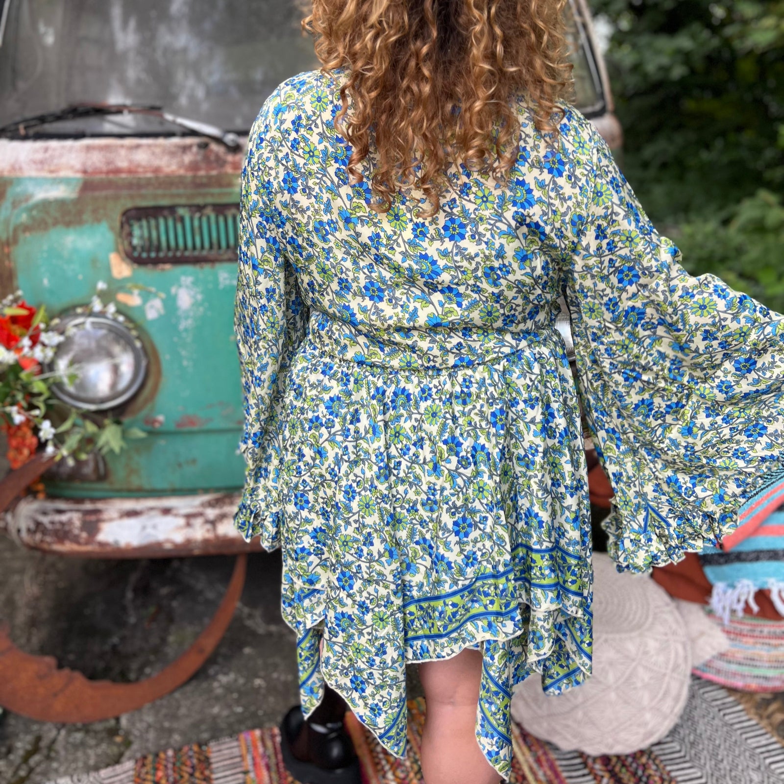 A woman wearing the green Hippie Bohemian Fairy Dress with Elastic Fairy Skirt in front of a vintage Volkswagen bus.