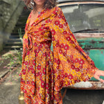 A woman wearing the red Hippie Bohemian Fairy Dress with Elastic Fairy Skirt in front of a vintage Volkswagen bus.