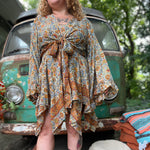 A woman wearing the orange and cream Hippie Bohemian Fairy Dress with Elastic Fairy Skirt in front of a vintage Volkswagen bus.