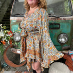 A woman wearing the orange and cream Hippie Bohemian Fairy Dress with Elastic Fairy Skirt in front of a vintage Volkswagen bus.