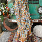 Someone wearing the orange & cream Hippie Floral Cinch Maxi Ruffle Skirt in front of a Volkswagen bus.