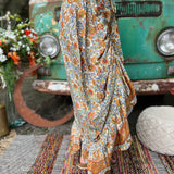 Someone wearing the orange & cream Hippie Floral Cinch Maxi Ruffle Skirt in front of a Volkswagen bus.