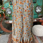 Someone wearing the orange & cream Hippie Floral Cinch Maxi Ruffle Skirt in front of a Volkswagen bus.