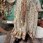 Someone wearing the orange & cream Hippie Floral Cinch Maxi Ruffle Skirt in front of a Volkswagen bus.