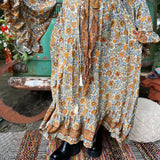 Someone wearing the orange & cream Hippie Floral Cinch Maxi Ruffle Skirt in front of a Volkswagen bus.