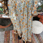 Someone wearing the orange & cream Hippie Floral Cinch Maxi Ruffle Skirt in front of a Volkswagen bus.