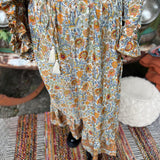Someone wearing the orange & cream Hippie Floral Cinch Maxi Ruffle Skirt in front of a Volkswagen bus.
