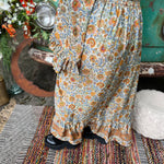 Someone wearing the orange & cream Hippie Floral Cinch Maxi Ruffle Skirt in front of a Volkswagen bus.