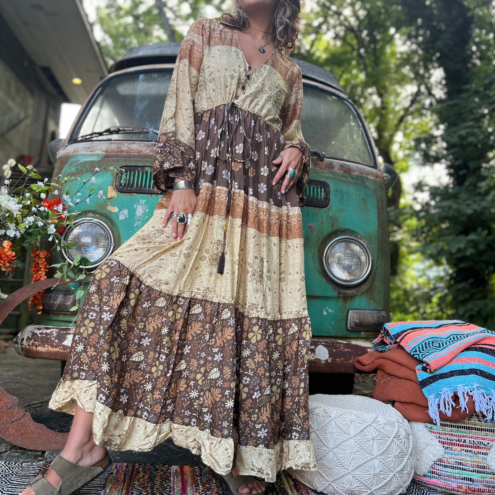 A woman wearing the Earthy Solstice Boho Bell Sleeve Maxi Dress in front of a vintage Volkswagen bus.