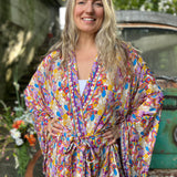 A woman wearing the Rainbow Hippie Boho Psychedelic Kimono Robe in front of a vintage Volkswagen bus.