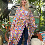 A woman wearing the Rainbow Hippie Boho Psychedelic Kimono Robe in front of a vintage Volkswagen bus.