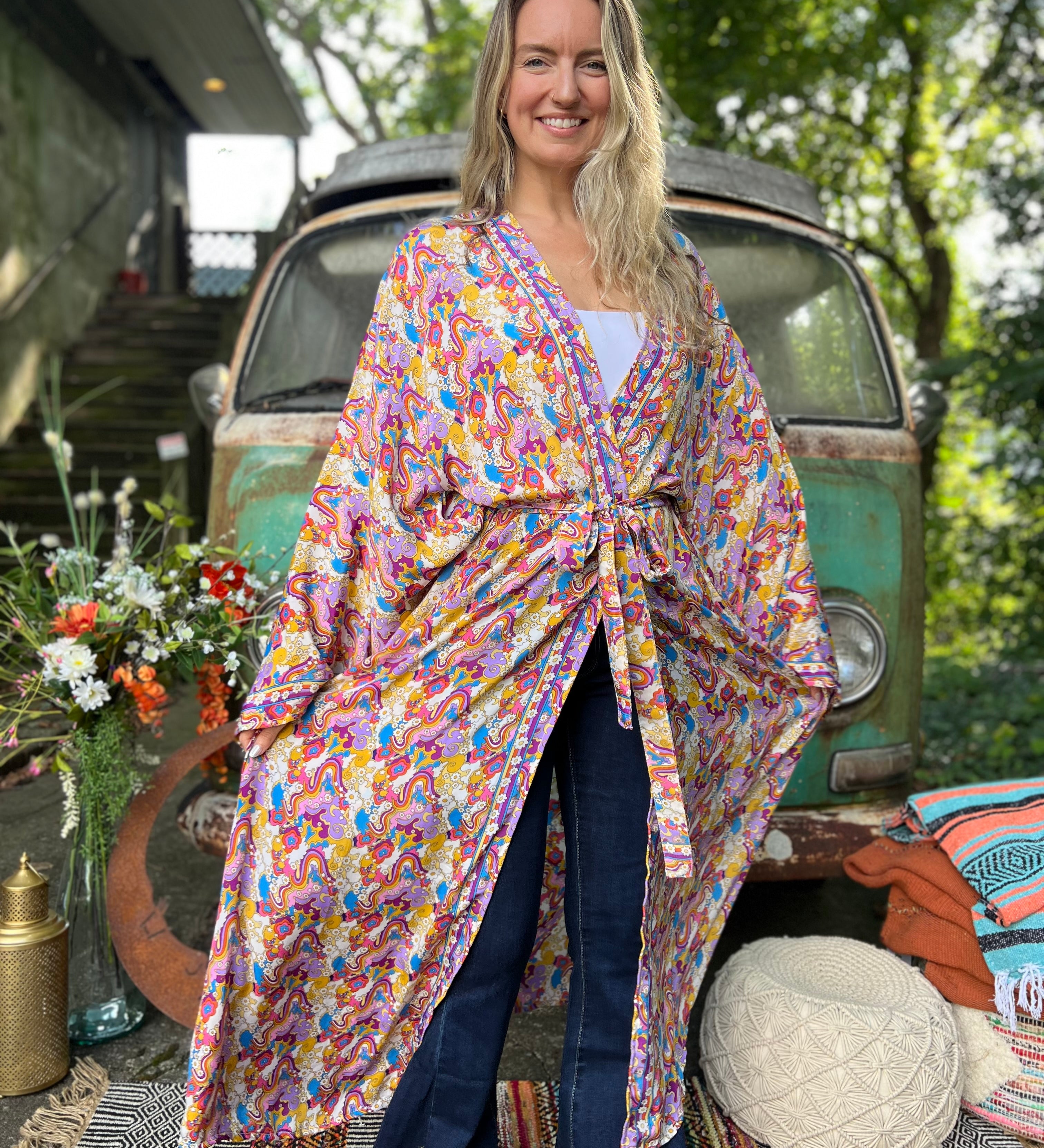 A woman wearing the Rainbow Hippie Boho Psychedelic Kimono Robe in front of a vintage Volkswagen bus.