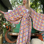 A woman wearing the Rainbow Hippie Boho Psychedelic Kimono Robe in front of a vintage Volkswagen bus.