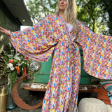 A woman wearing the Rainbow Hippie Boho Psychedelic Kimono Robe in front of a vintage Volkswagen bus.