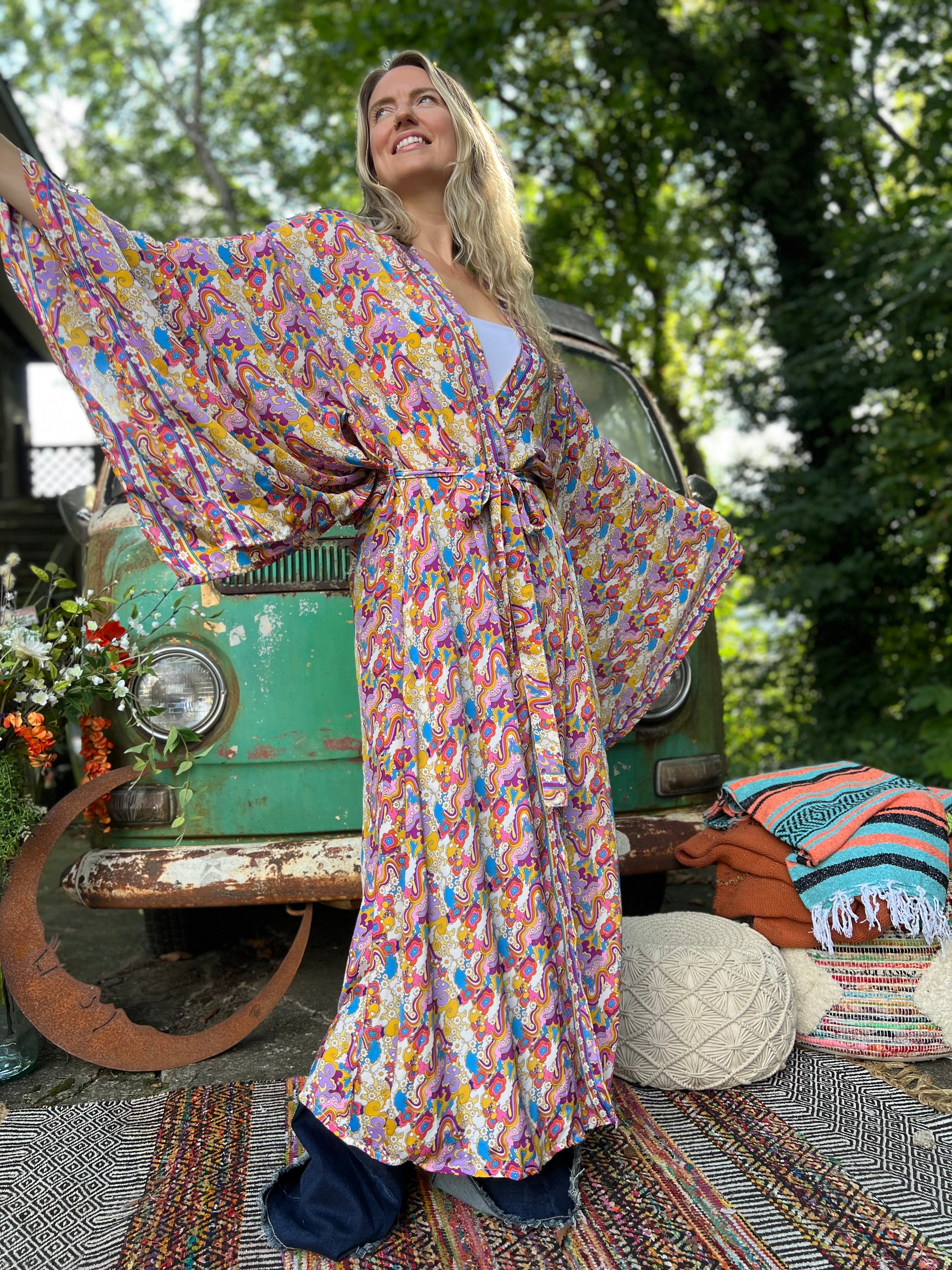 A woman wearing the Rainbow Hippie Boho Psychedelic Kimono Robe in front of a vintage Volkswagen bus.
