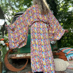 A woman wearing the Rainbow Hippie Boho Psychedelic Kimono Robe in front of a vintage Volkswagen bus.