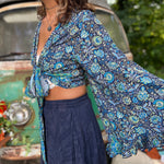 A woman wearing the blue Hippie Bohemian Bell Sleeve Wrap Top with black pants in front of a rusted vintage Volkswagen bus.