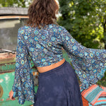 A woman wearing the blue Hippie Bohemian Bell Sleeve Wrap Top with black pants in front of a rusted vintage Volkswagen bus.