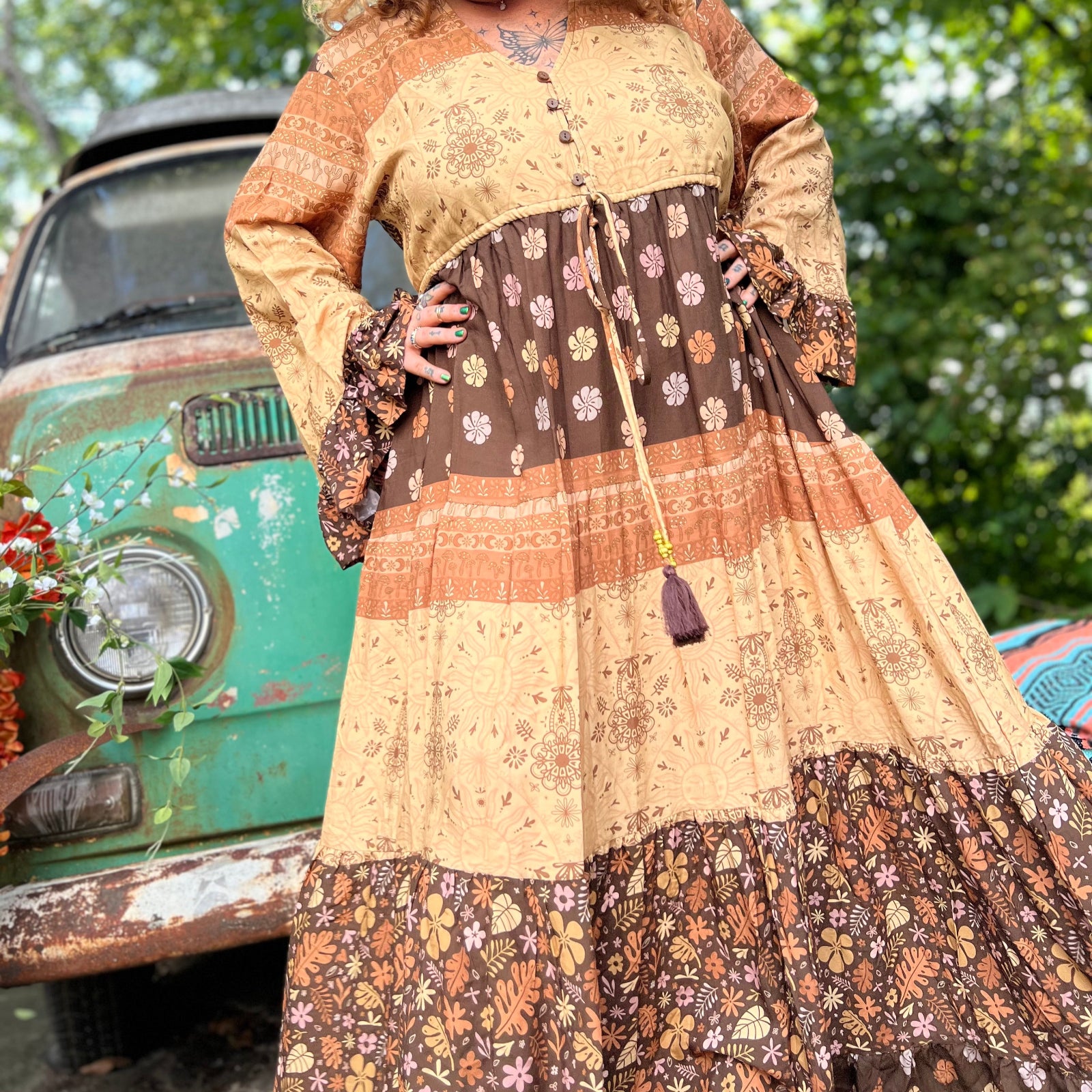 A woman wearing the Earthy Solstice Boho Bell Sleeve Maxi Dress in front of a vintage Volkswagen bus.