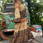 A woman wearing the Earthy Solstice Boho Bell Sleeve Maxi Dress in front of a vintage Volkswagen bus.