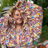 A woman wearing the rainbow Hippie Bohemian Bell Sleeve Wrap Top with black pants in front of a rusted vintage Volkswagen bus.
