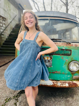 twirling boho girl in denim dress in front of VW bus