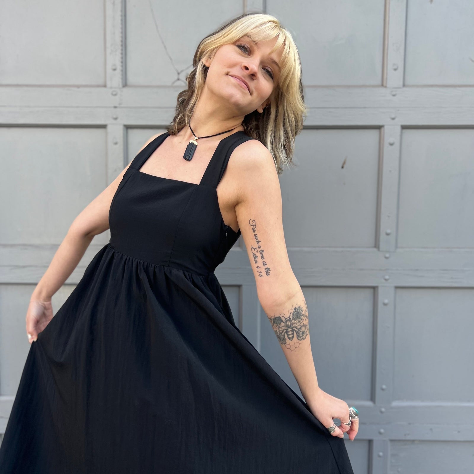 A woman wearing the Black Woven Polyester Nylon Back Cross Strap Midi Dress with sandals and a black crystal necklace.