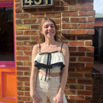 A woman wearing the Contrast Cotton Flare Bow Top with white jeans in front of a brick wall.