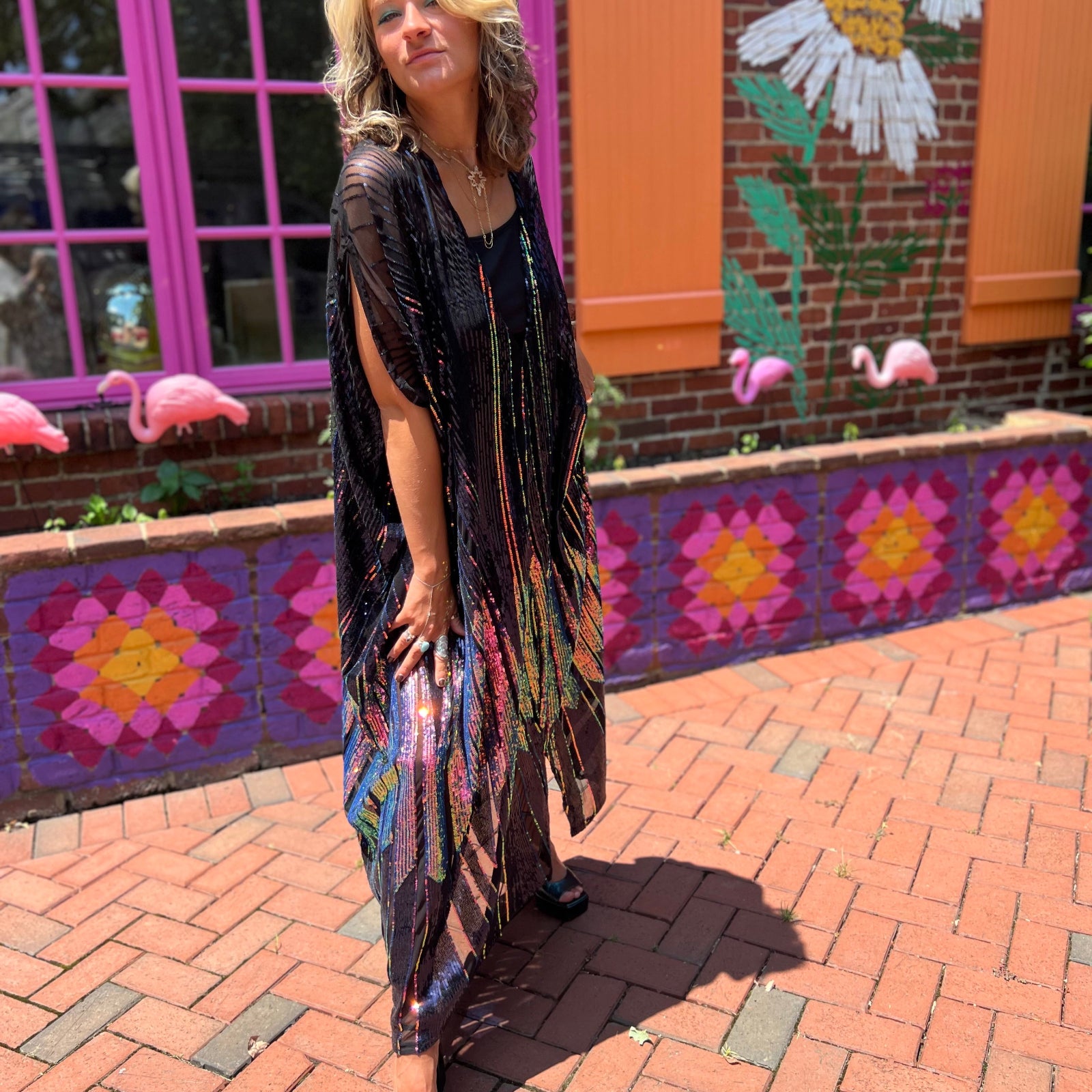A woman wearing the Midnight Lotus Caftan with a black dress and heels.