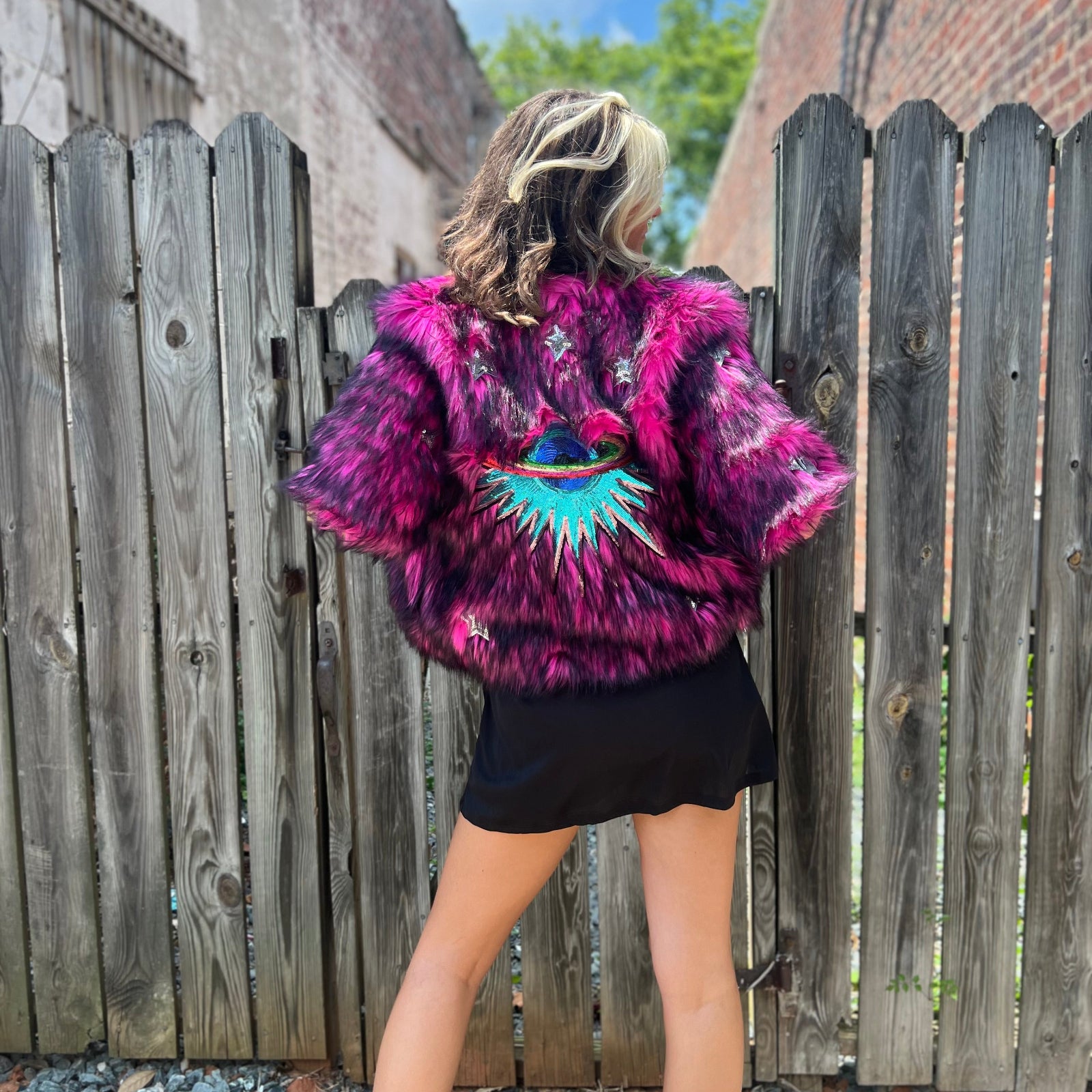 A woman wearing the Faux Fur Jacket in Monster Pink by Jennafer Grace with a black dress.