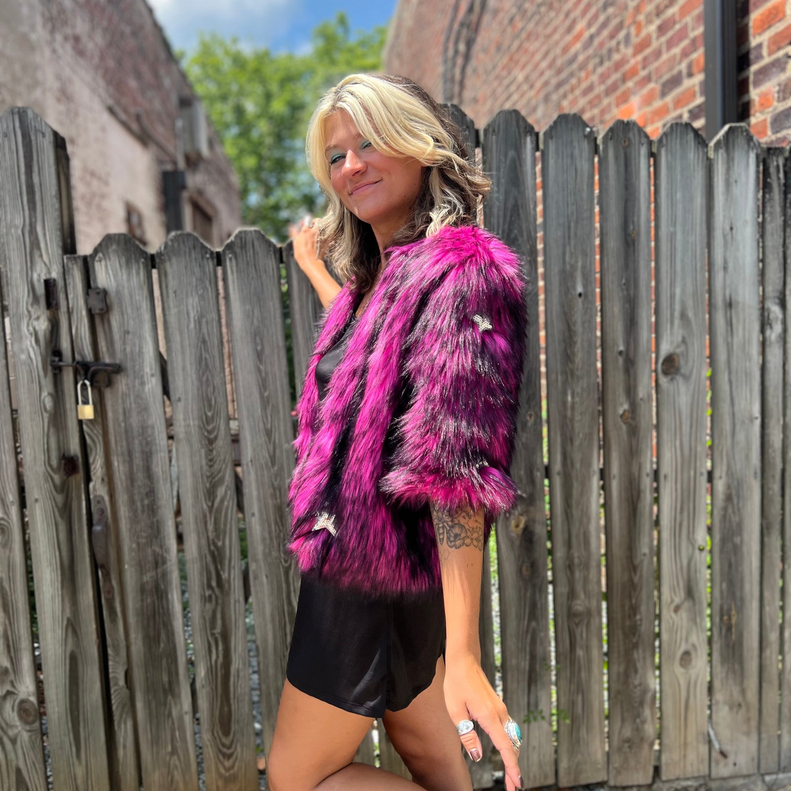 A woman wearing the Faux Fur Jacket in Monster Pink by Jennafer Grace with a black dress.
