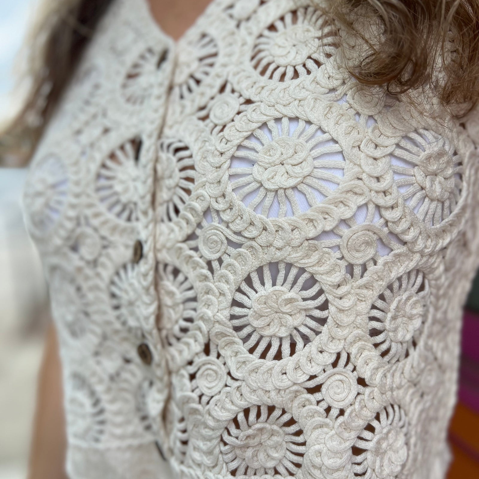 A woman wearing the beige V-Neck Crochet Button Up Vest.