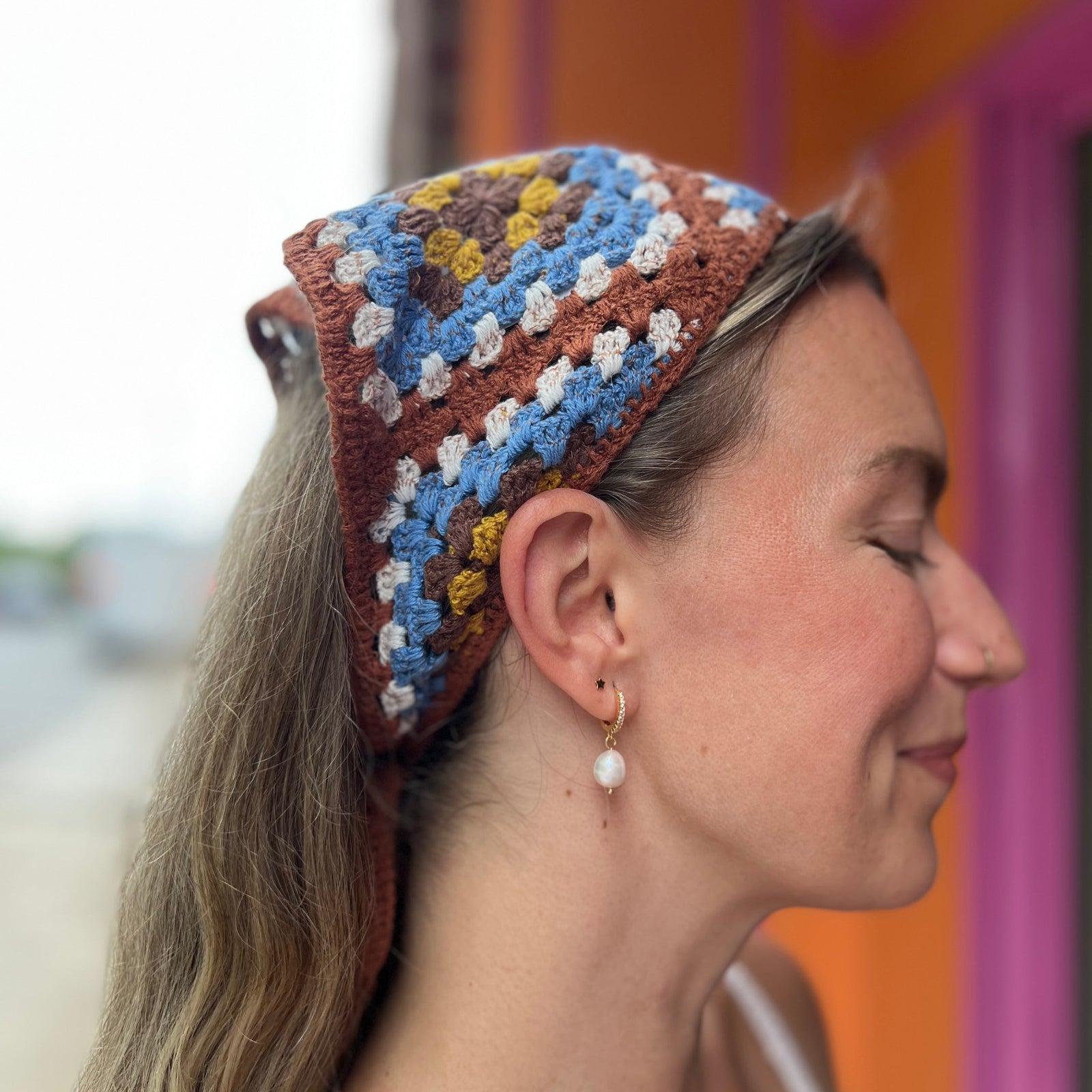 A woman wearing the Handmade Granny Square Crochet Headband around her head.