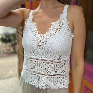 A woman wearing the white Solid Color Crochet Lace Hollow Camisole Top with beige linen pants.