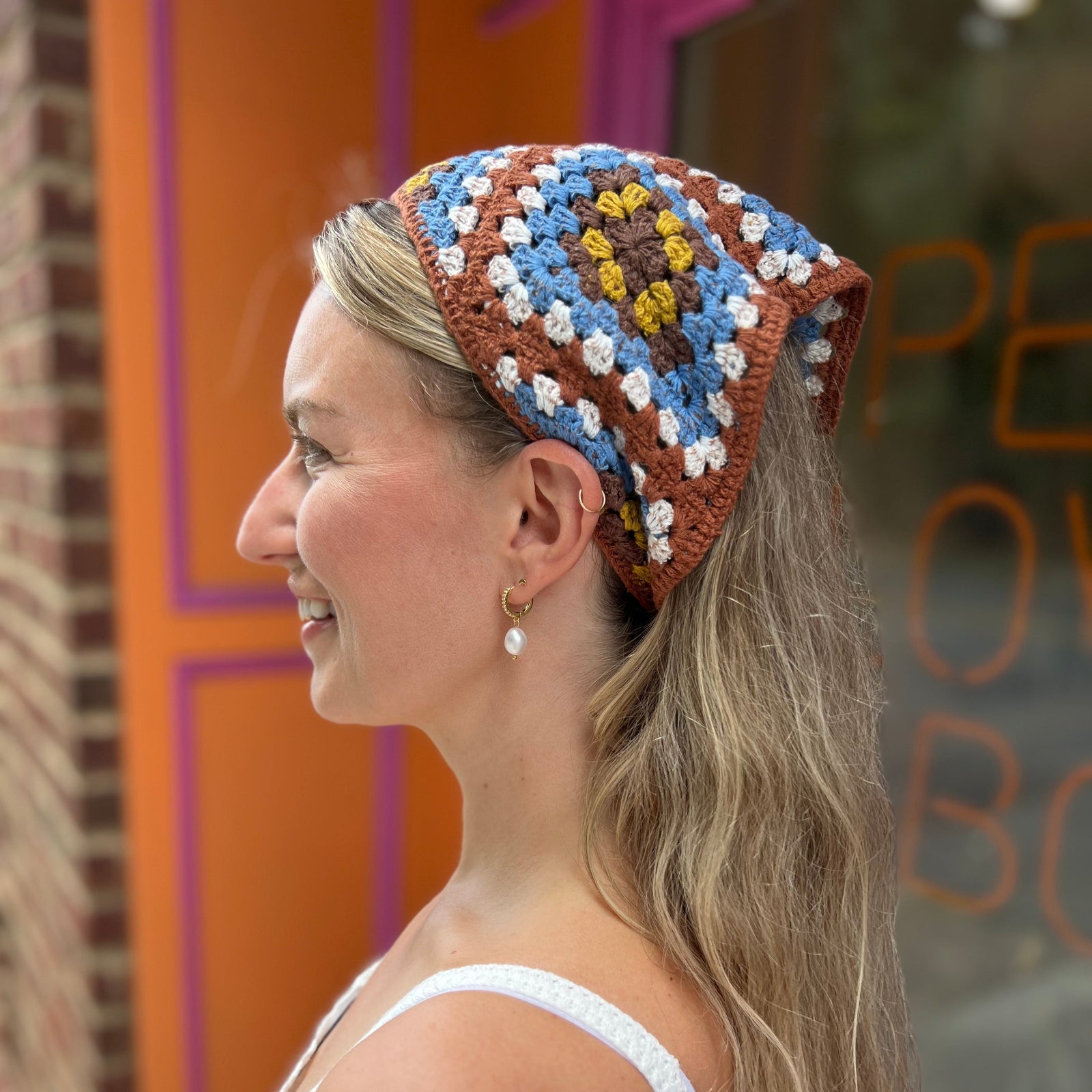 A woman wearing the Handmade Granny Square Crochet Headband around her head.