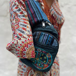 Someone wearing the Cotton Peace Sign Crossbody Bag in front of a white cement wall.