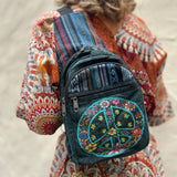 Someone wearing the Cotton Peace Sign Crossbody Bag in front of a white cement wall.