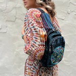 Someone wearing the Cotton Peace Sign Crossbody Bag in front of a white cement wall.