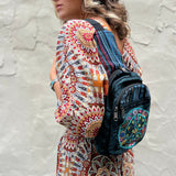 Someone wearing the Cotton Peace Sign Crossbody Bag in front of a white cement wall.