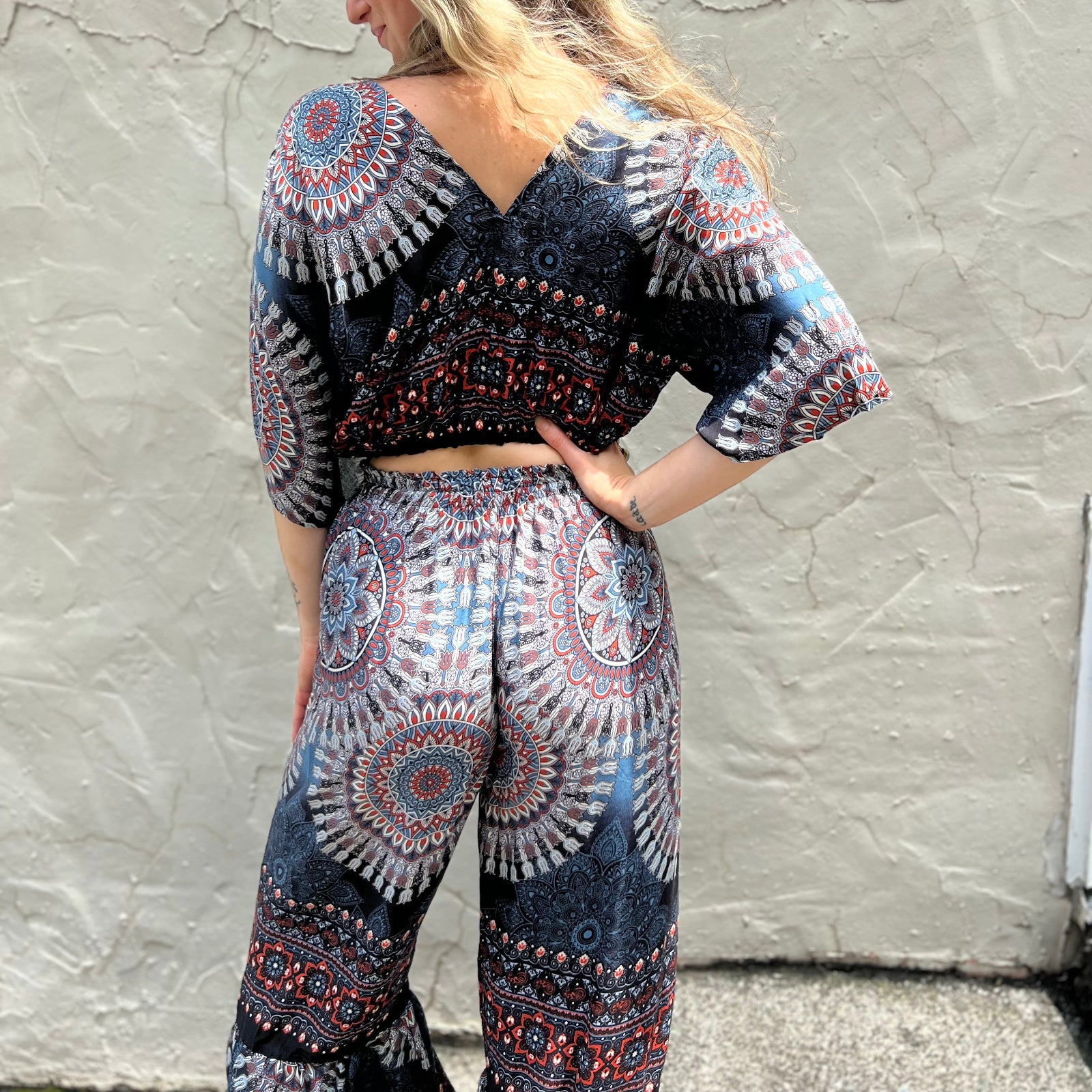 A woman wearing the blue Woven Floral Paisley Top and Trouser Set in front of a white wall.