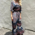 A woman wearing the blue Woven Floral Paisley Top and Trouser Set in front of a white wall.