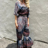 A woman wearing the blue Woven Floral Paisley Top and Trouser Set in front of a white wall.